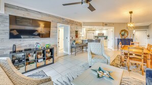 A spacious living room with a modern TV, a ceiling fan, and a dining area with a wooden table and chairs. - New Smyrna Beach Condo w/ Balcony & Ocean Walk (New Smyrna Beach)