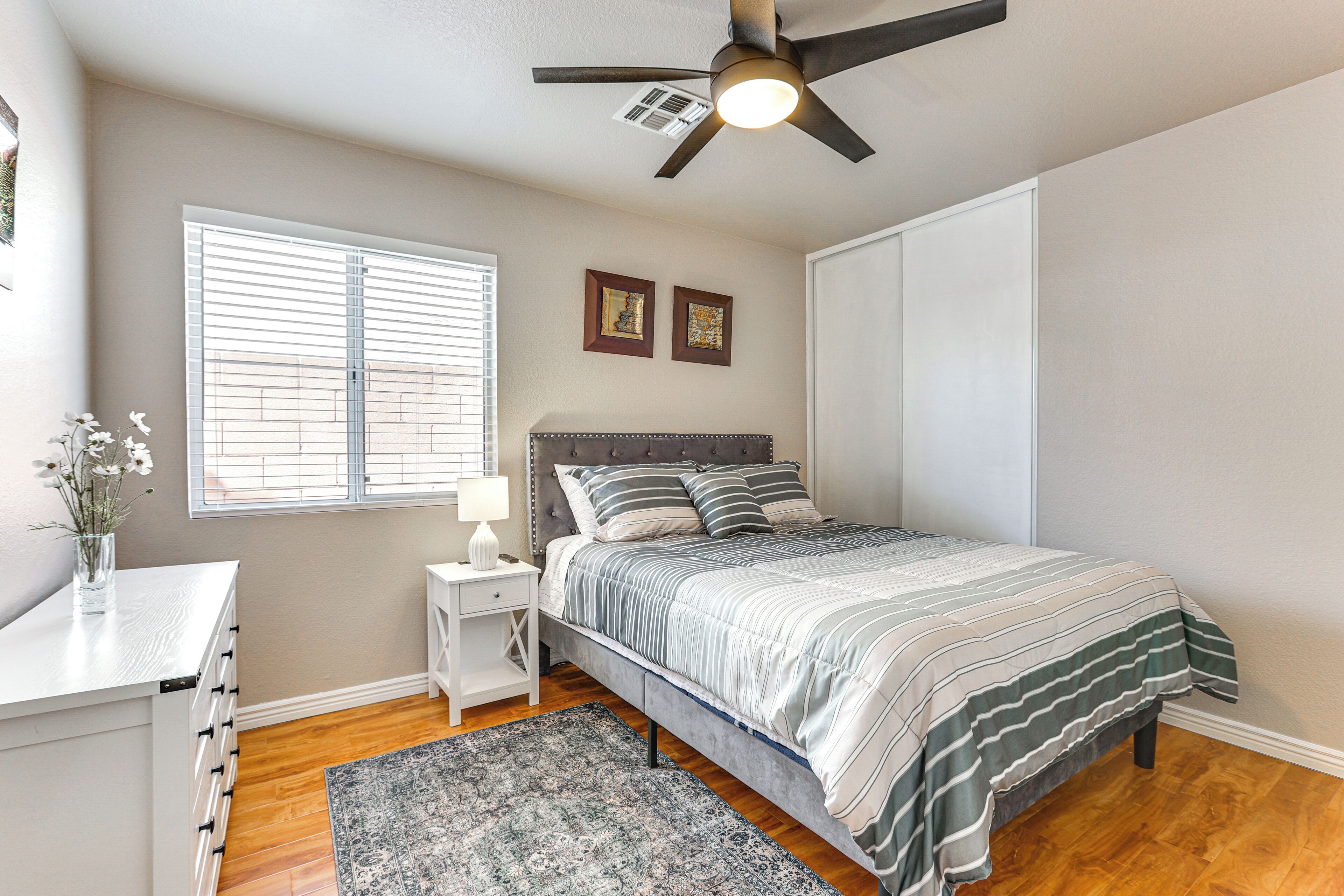 A bedroom with a bed, bedside table, nightstand, and a ceiling fan.