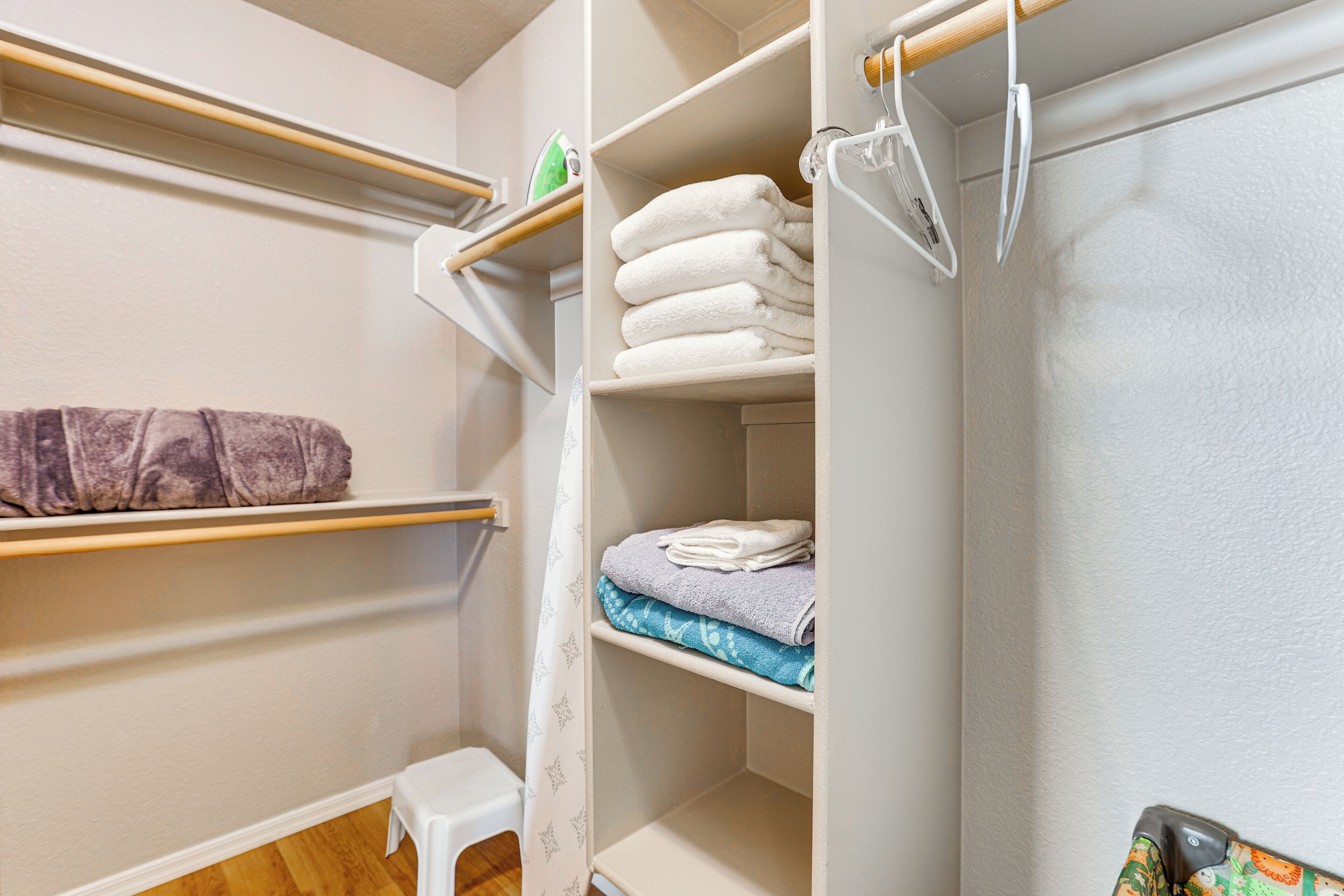 A closet with shelves holding folded towels and a hanging rack.