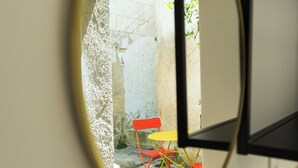 Un miroir rond reflétant un espace extérieur avec une chaise rouge et une table jaune.