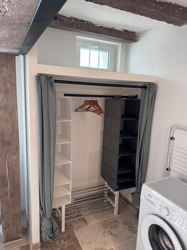 Un espace buanderie comprenant un lave-linge, un étendoir et un meuble de rangement avec des étagères.