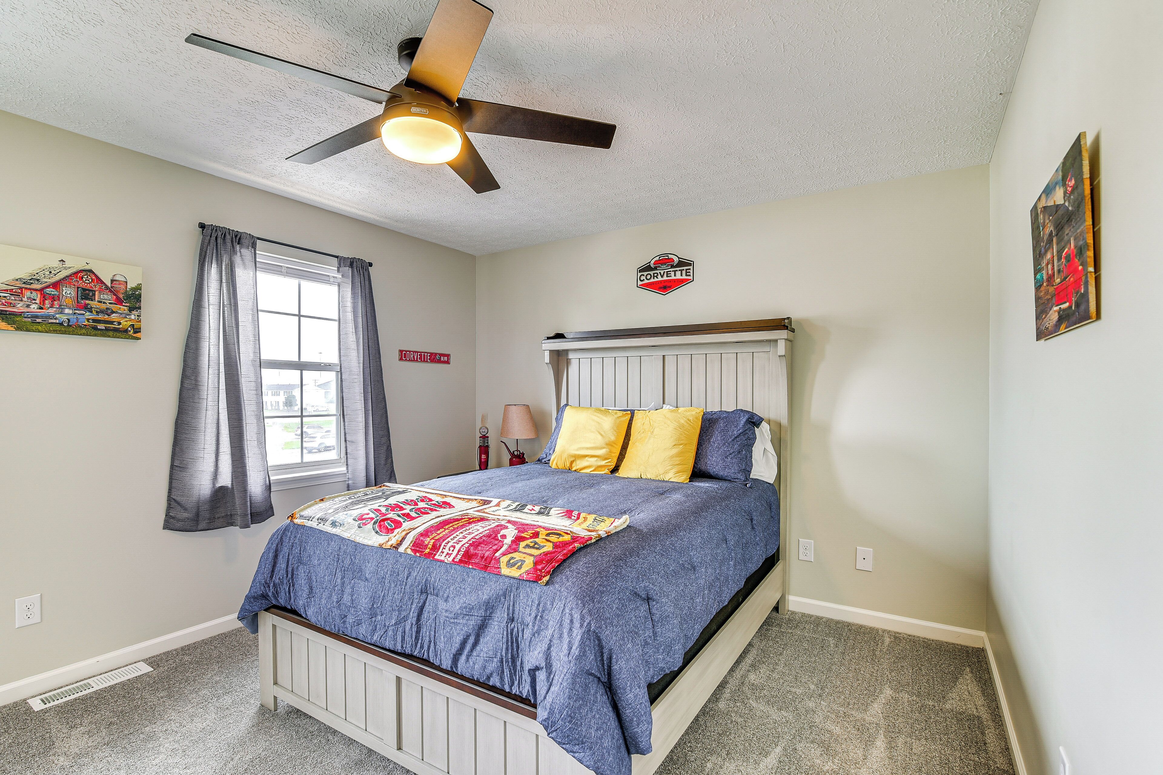 A bedroom with a bed, a ceiling fan, a window with curtains, and a radiator.