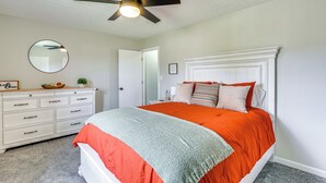 A bedroom with a bed, a dresser, a ceiling fan, a mirror, and a door. - Inviting Bowling Green Escape w/ Smart Tvs! (Bowling Green)