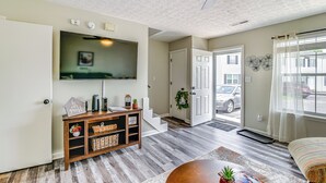 A living room with a flat-screen TV, wooden entertainment unit, and a ceiling fan. - Inviting Bowling Green Escape w/ Smart Tvs! (Bowling Green)