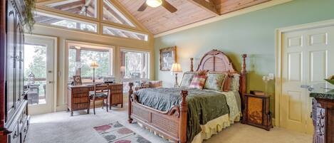 A bedroom with a wooden ceiling, a large bed, a desk, and a chair.