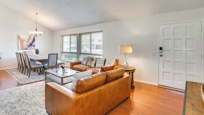 A living room with a brown leather sofa, a glass coffee table, a dining table with chairs, and a lamp. - Huntington Beach Home: Fire Pit, Grill + More! (Huntington Beach)