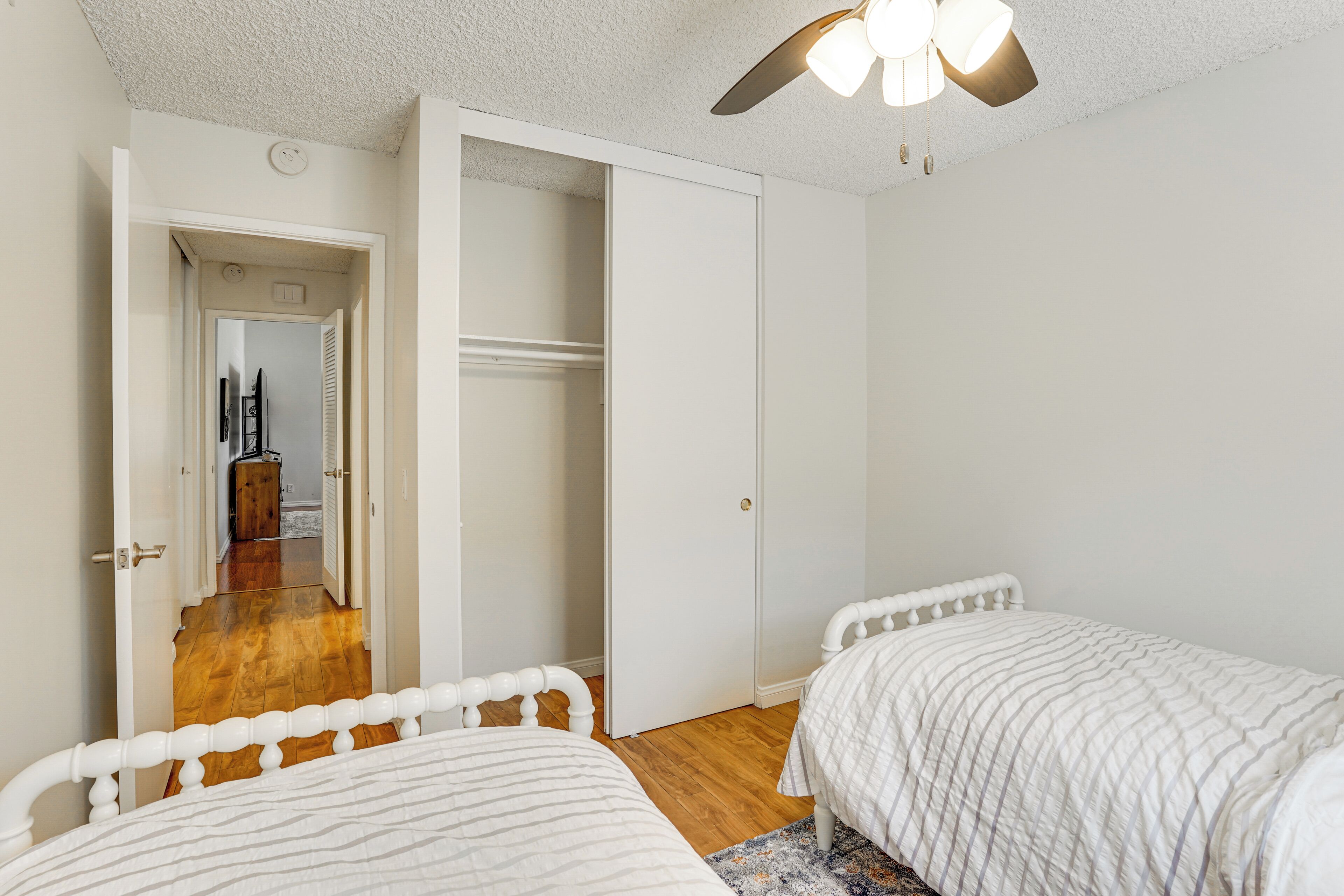 A bedroom with two beds, a walk-in closet, and a ceiling fan.
