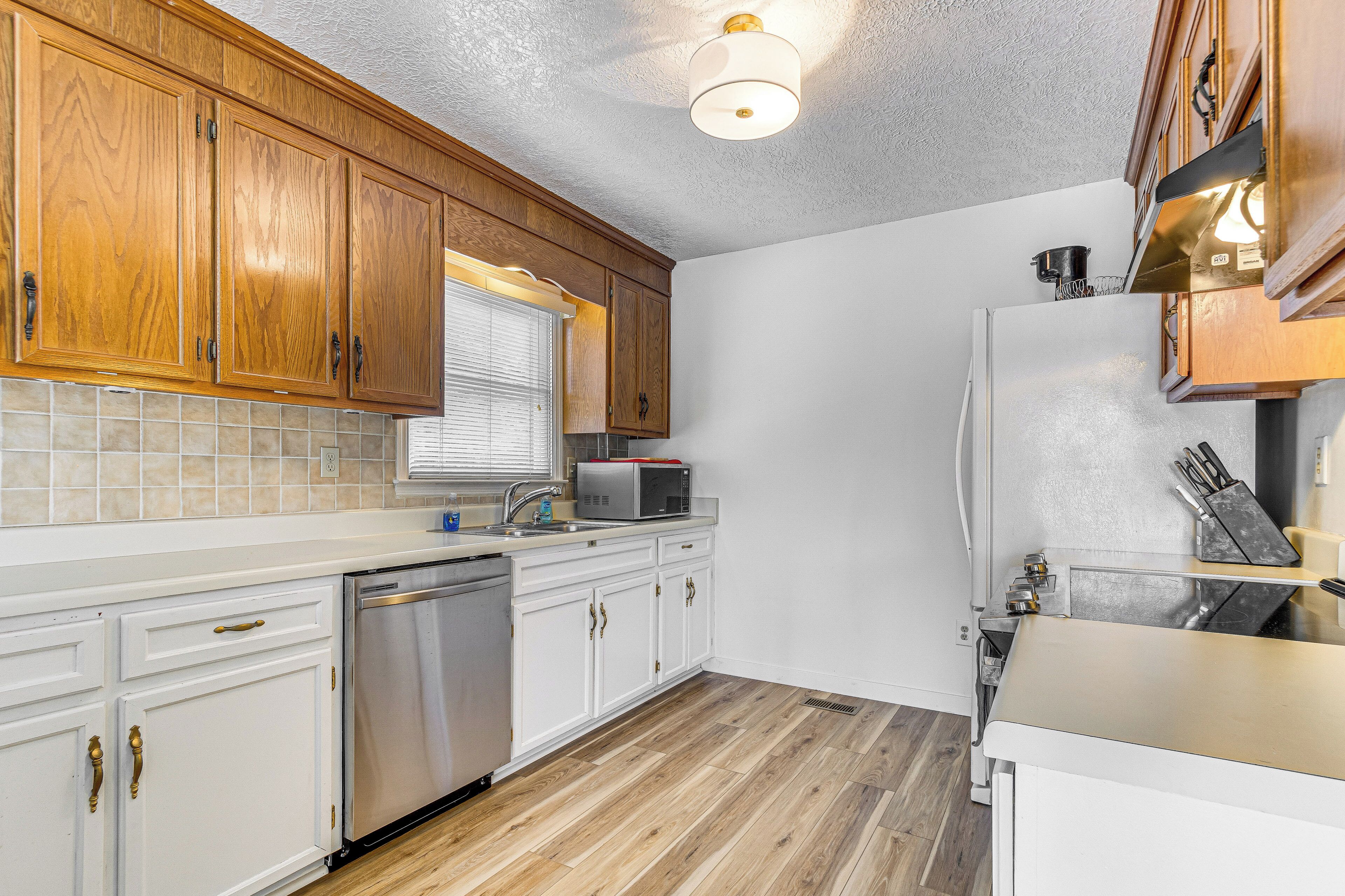 A kitchen with wooden cabinets, a stainless steel dishwasher, a microwave, and a refrigerator.