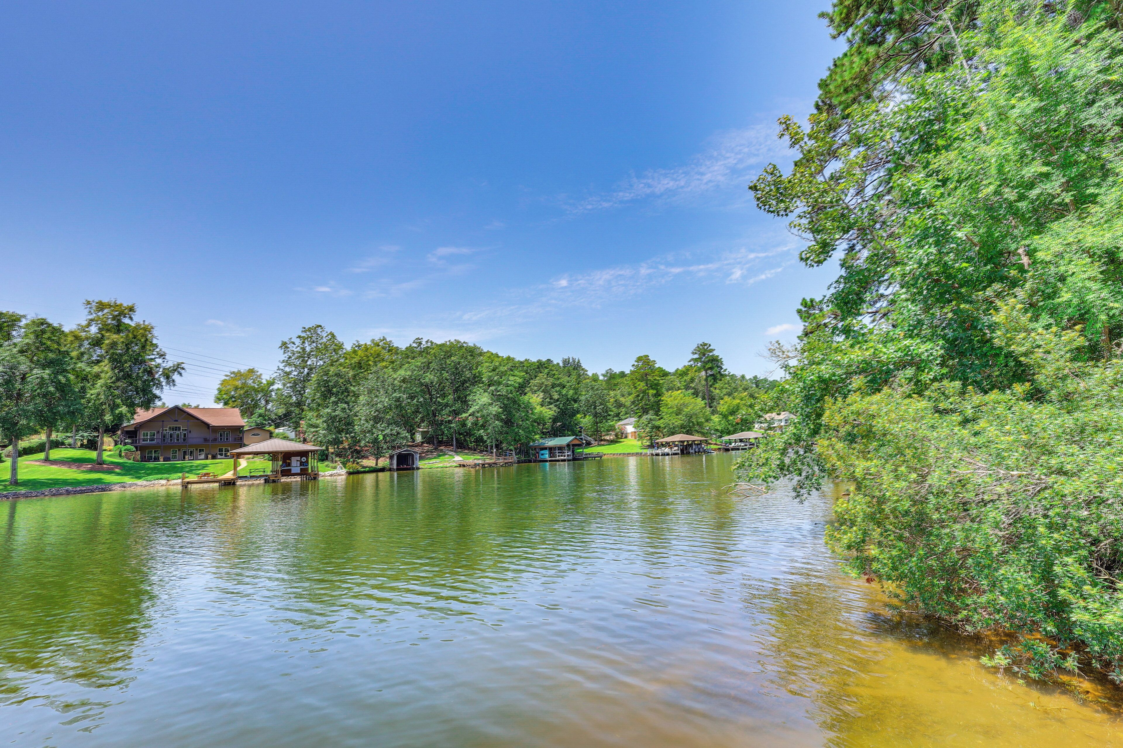 A lakeside property with a large house, dock, and surrounding greenery.