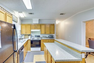 Una cocina compacta con armarios de madera, horno empotrado, refrigerador y encimeras de granito.