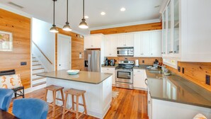 A modern kitchen with white cabinets, stainless steel appliances, and a wooden island with stools. - Beach & Pool Access: Peaceful St Teresa House (Carrabelle)