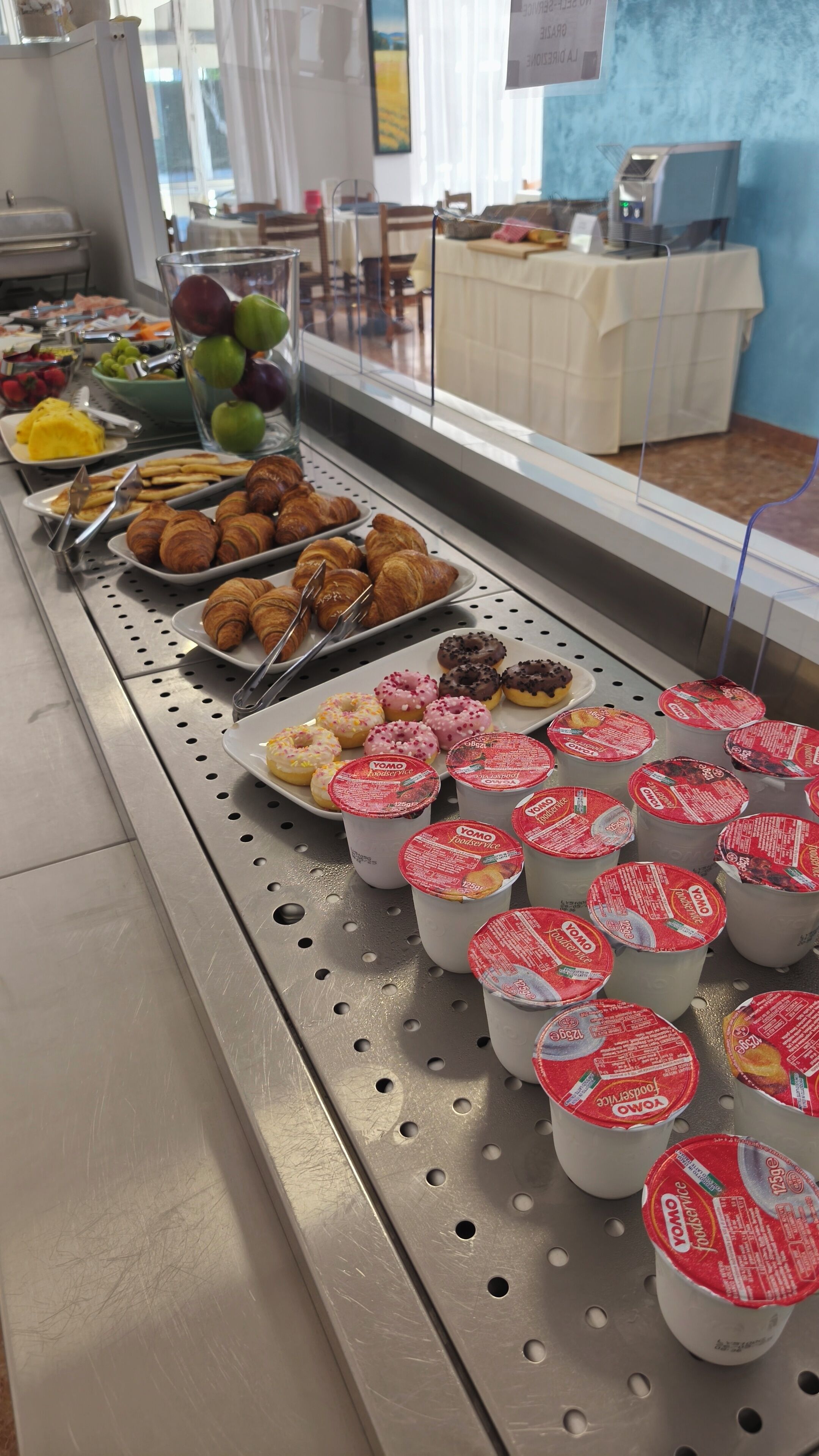 Un buffet proposant des pâtisseries, des beignets et des yaourts en portions individuelles.