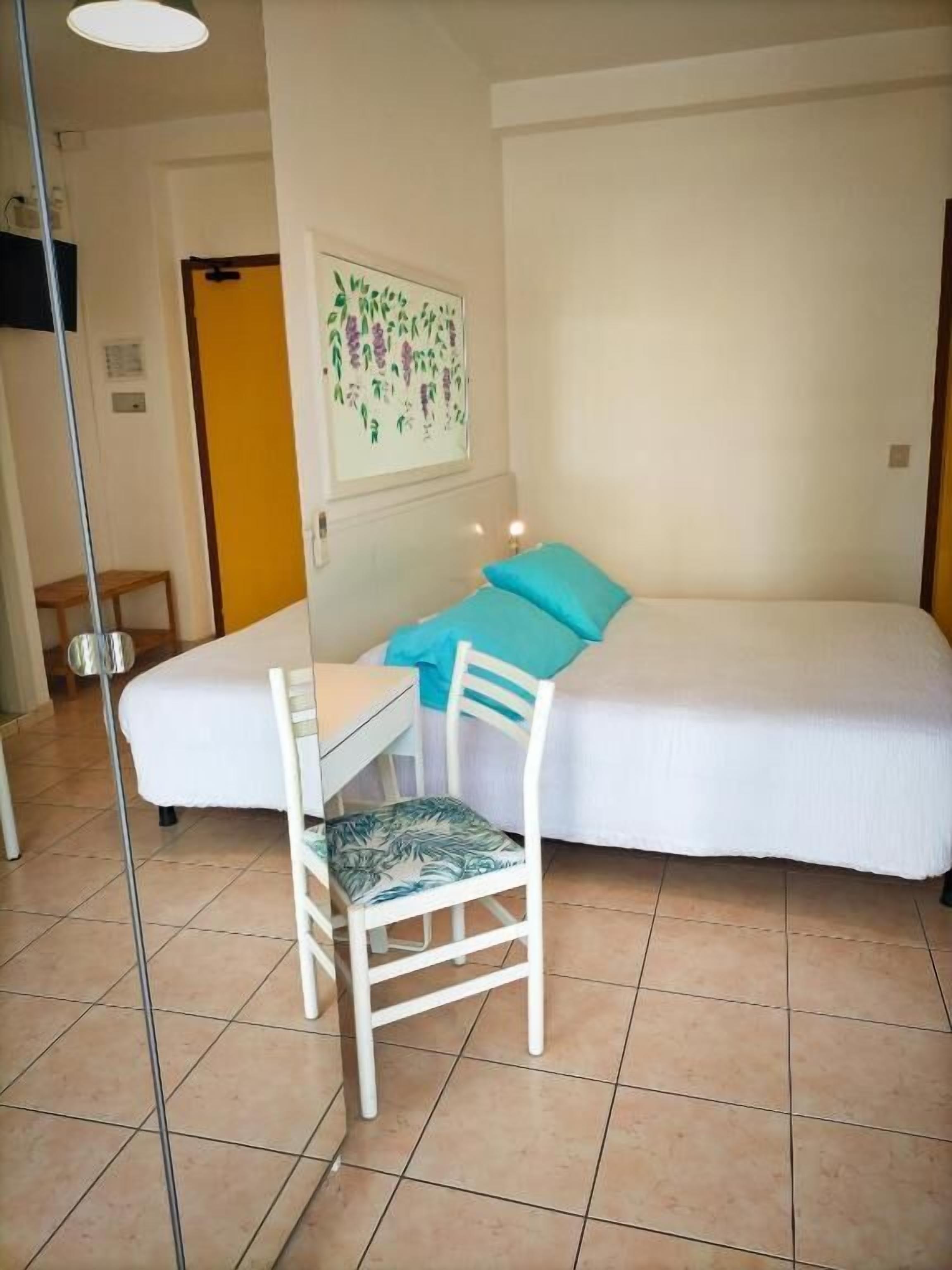 A small, clean room with a bed, a desk, and a chair.