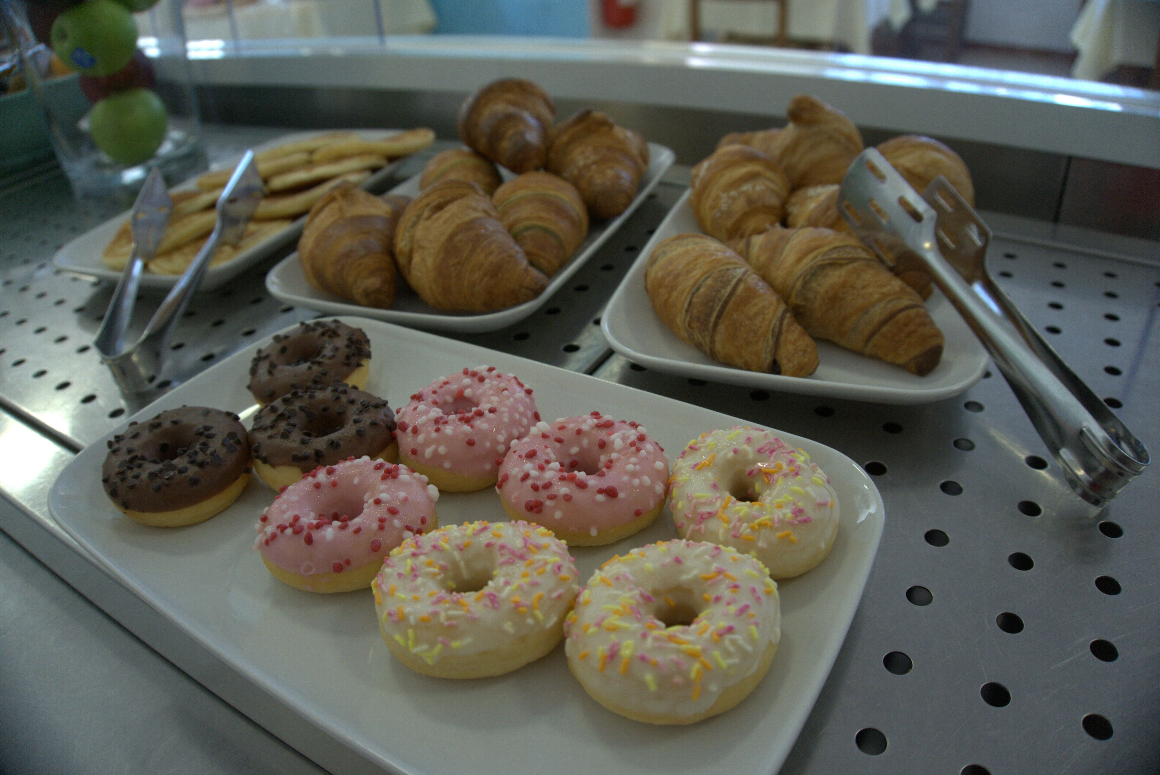 Esposizione di dolci che include croissant e ciambelle con diversi condimenti.