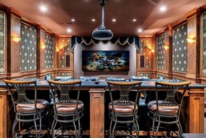 Eine Bar mit einer langen Theke, vier Barhocker und einem großen gerahmten Kunstwerk darüber.