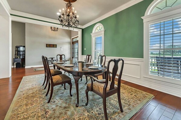 A dining area with a round table, chairs, and a chandelier.