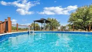 A clear blue pool with a wooden deck, a covered seating area, and a fenced perimeter. - The Green Ranch House-Pool-Theatre-Hot Tub-Game Ro (Lorena)