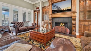 A spacious living room with leather sofas, a glass coffee table, and a fireplace with a stone facade. - The Green Ranch House-Pool-Theatre-Hot Tub-Game Ro (Lorena)