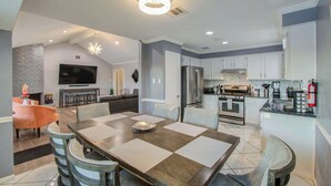A modern kitchen with white cabinets, a stainless steel refrigerator, and a built-in oven. - Your Houston Vacation Getaway, 4-BD, Pool, Patio (Houston)