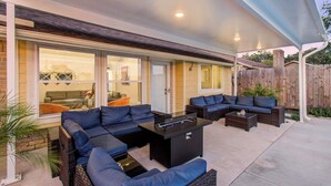 An outdoor patio with a sectional sofa, a coffee table, and a fire pit. - Your Houston Vacation Getaway, 4-BD, Pool, Patio (Houston)