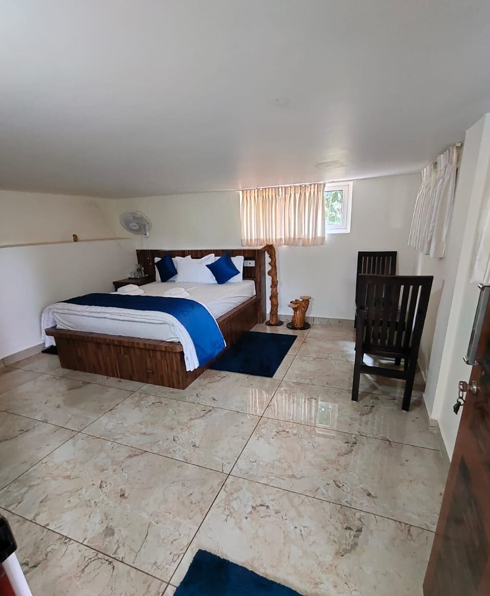 Quarto com cama, cadeira, mesa de cabeceira e janela com cortinas.