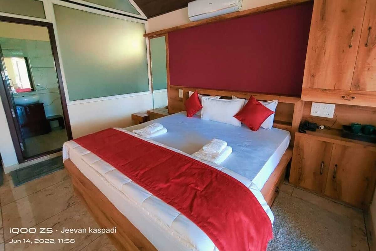 A hotel room with a bed, wooden headboard, and a red accent wall.