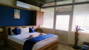 Un dormitorio con una cama de madera, una pared azul, una ventana con persianas y una estatua.
