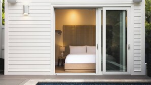 A bedroom with a bed, a nightstand, a lamp, and a window with curtains. - The Rigby House - Pool, One block from Duval St (Key West)