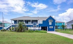A two-story house with a blue exterior, a front porch, and a staircase leading to the entrance. - Yoho Hideout 4 Bedroom Home by RedAwning (Port Bolivar)