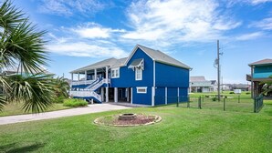 A blue two-story house with a front porch and a staircase leading to the entrance. - Yoho Hideout 4 Bedroom Home by RedAwning (Port Bolivar)