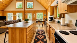 Una cocina amplia con armarios de madera, una isla central y un comedor con vistas al exterior.
