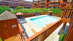 A pool area with a wooden deck, lounge chairs, and a sign indicating a pool area. - Sunset Landing 24 2 Bedroom Townhouse by RedAwning (Ocean City)