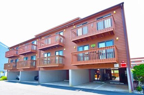 A multi-story building with balconies and a parking area in front. - Sunset Landing 24 2 Bedroom Townhouse by RedAwning (Ocean City)