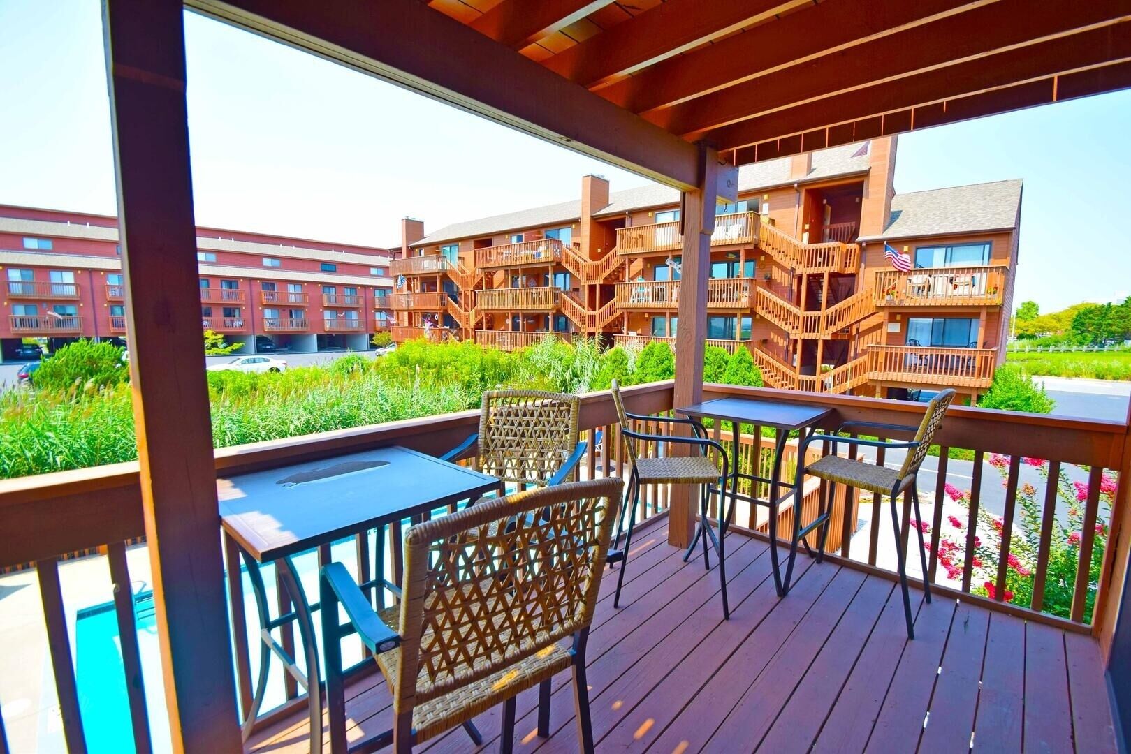 A wooden deck with outdoor seating, overlooking a residential area with multi-story buildings.