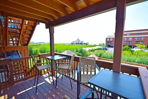 A wooden deck with a table and chairs, overlooking a green field and buildings. - Sunset Landing 24 2 Bedroom Townhouse by RedAwning (Ocean City)