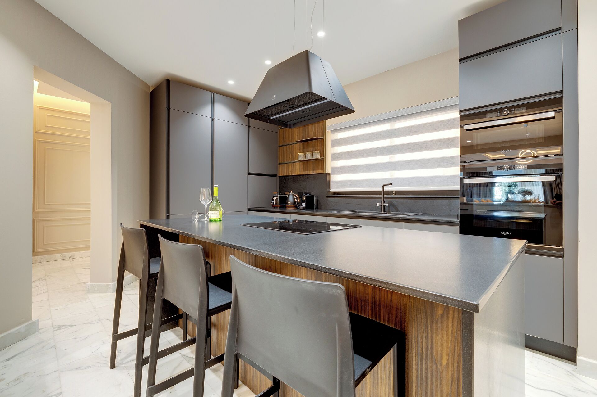 A modern kitchen with a central island, stainless steel appliances, and a wooden accent wall.