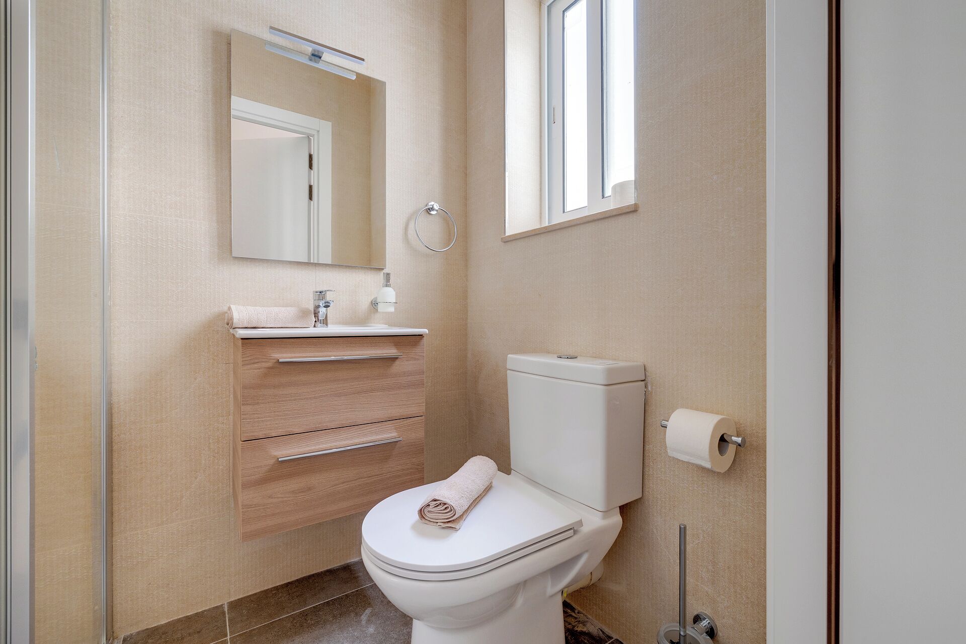 A modern bathroom with a toilet, sink, and mirror.