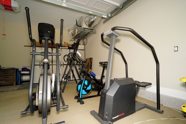 A home gym with various exercise equipment including a stationary bike, elliptical, and treadmills. - Charming 3-bedroom house with WiFi, fitness room on Gated property (Jennings)