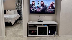 A bedroom with a bed, a TV mounted on the wall, and a white console table below.