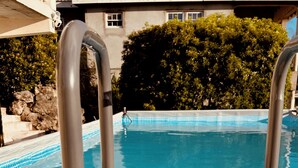 A pool with metal ladders and a tiled deck.