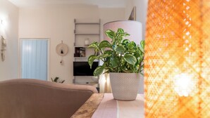 A living room with a potted plant on a wooden table, a sofa, and a lamp.
