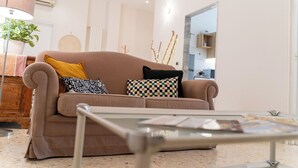 A living room with a beige sofa, a glass coffee table, and a potted plant.