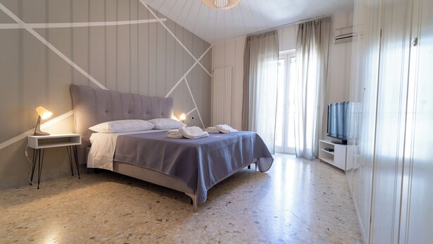 A modern bedroom with a large bed, bedside lamps, a television, and a ceiling light fixture.