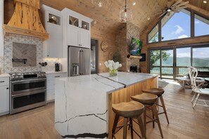 Una cocina moderna con una isla grande, electrodomésticos de acero inoxidable y vistas al exterior.