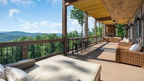 A wooden deck with outdoor seating, a view of the mountains, and a covered area with a ceiling fan. - Elevated Escape Blue Ridge GA (Blue Ridge)