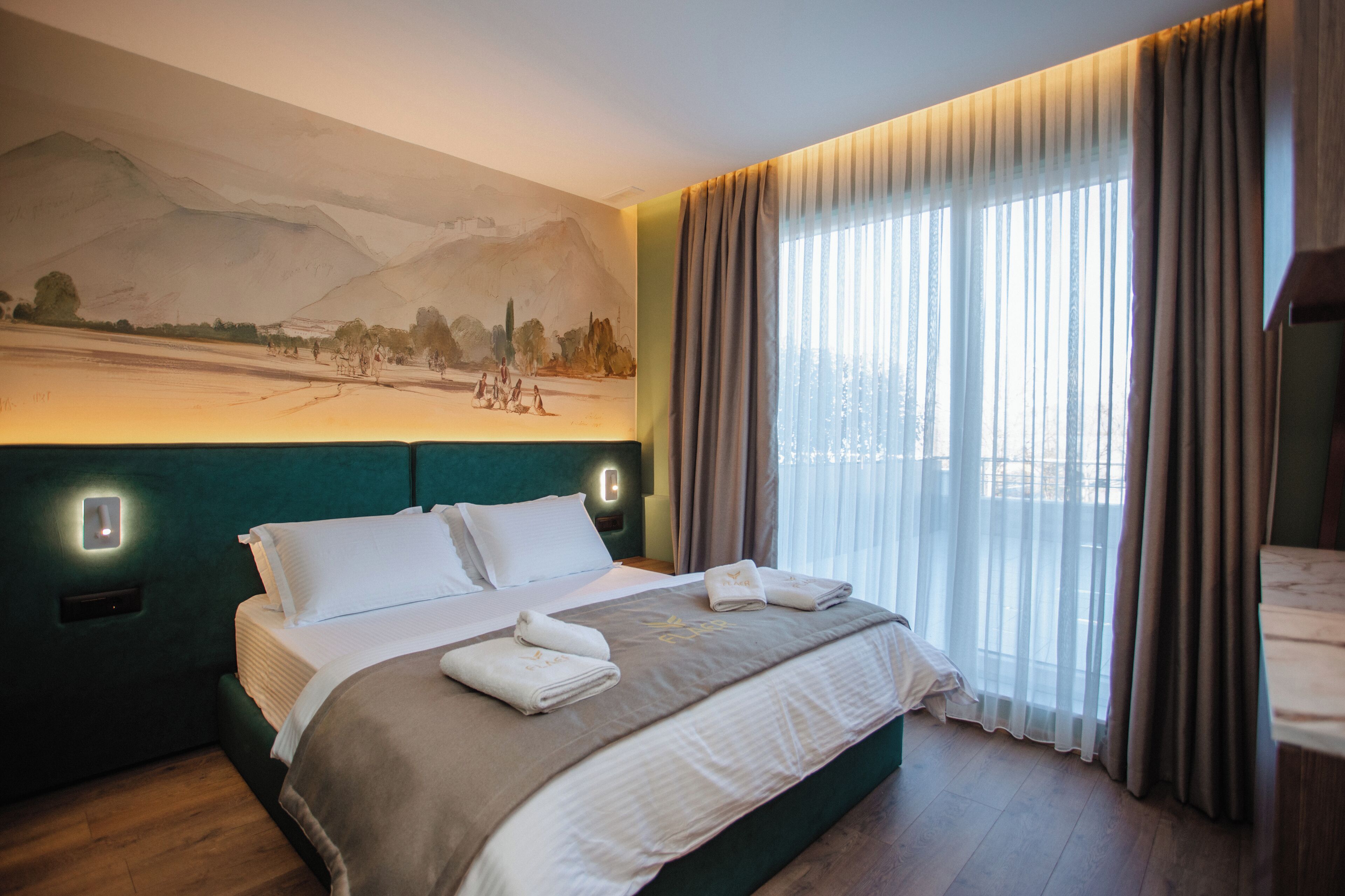 Habitación de hotel con una cama grande, un cuadro en la pared y vistas al exterior por la ventana.