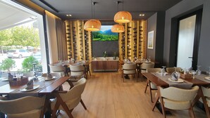 A restaurant with multiple dining tables, chairs, and a wine rack. - Hotel Flaer (Shkodër)