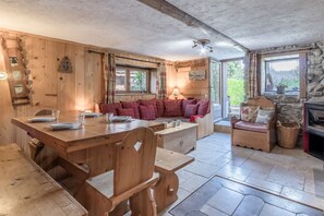 Cozy dining area with a wooden table and benches, a comfortable sofa, and a stone fireplace.
