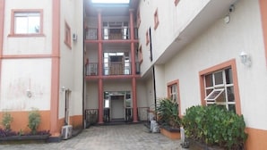 Un edificio de varios niveles con un patio central, balcones y plantas en macetas.