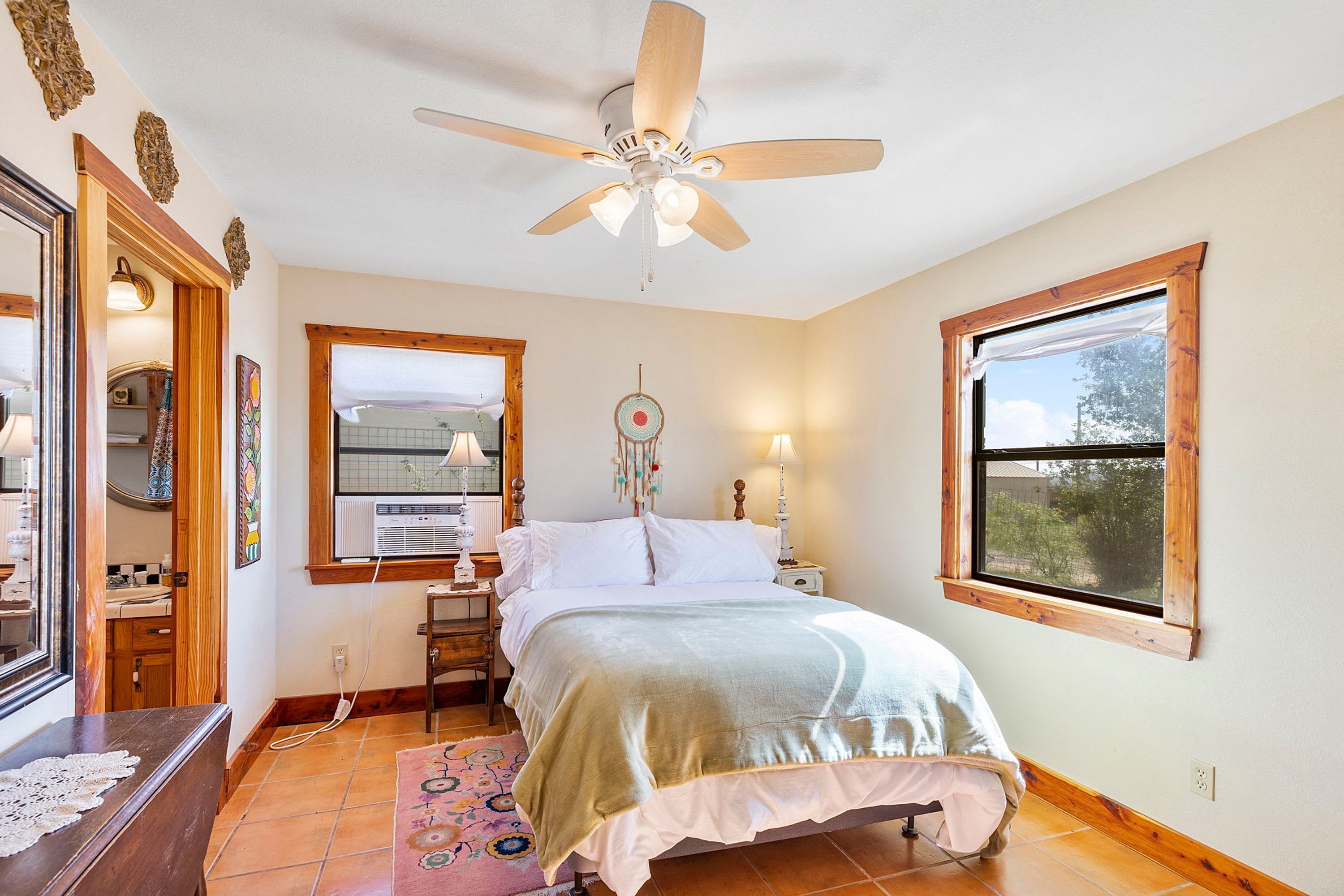 A bedroom with a bed, a ceiling fan, a window, and a bedside table.